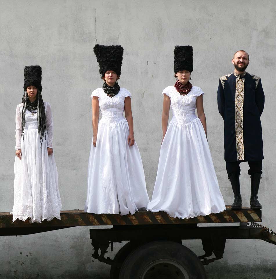 DakhaBrakha band members in Ukrainian dress standing on the back of a lorry 
