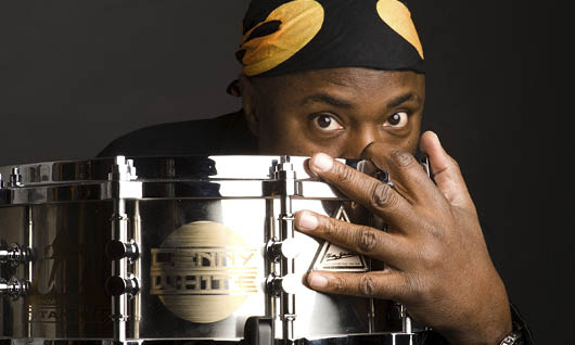 Lenny White peeking out from behind a snare drum